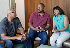 Group of three people sitting and talking.