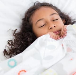 Child sleeping with covers up around their face as if scared.